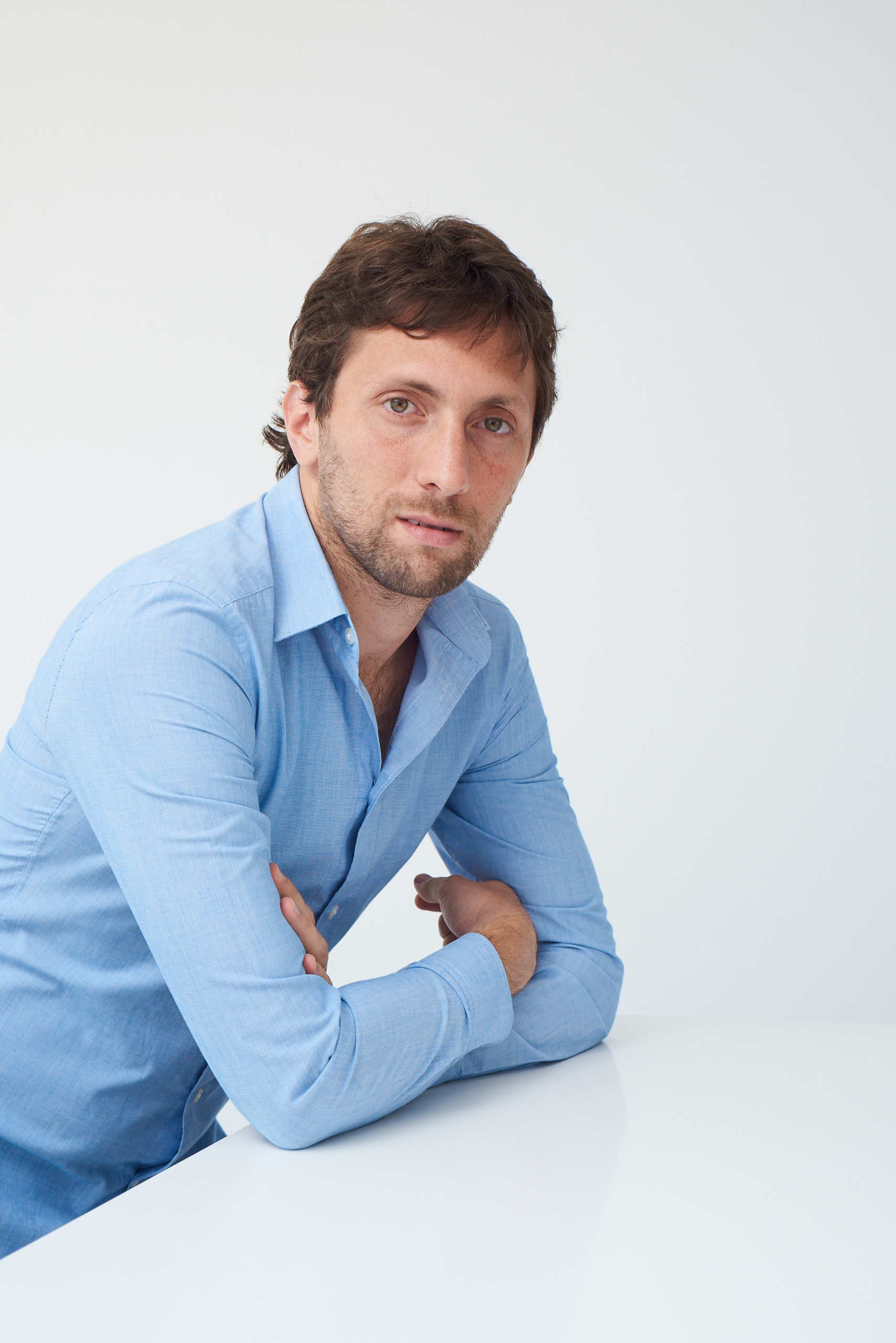Gaston Krasny, Argentine technology entrepreneur, leaning on a desk — professional press portrait